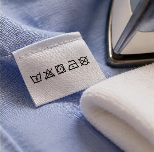Close-up of fabric care symbols on a light-blue shirt, checked before setting the iron temperature