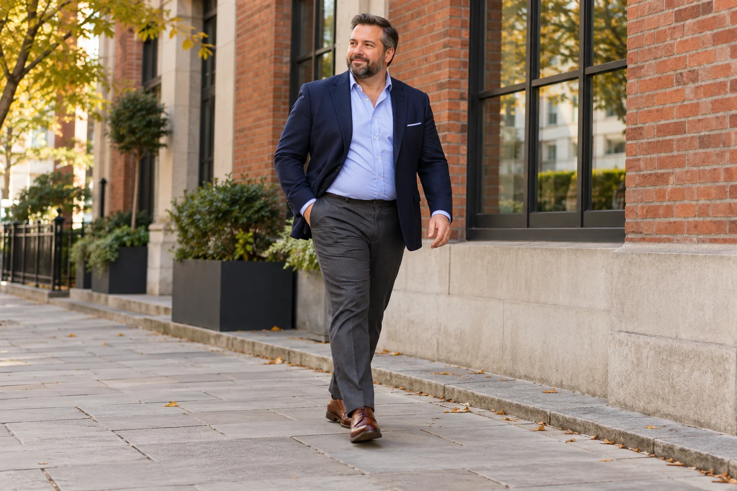 Man in navy blazer, pale blue open-collar shirt and charcoal trousers on a city street